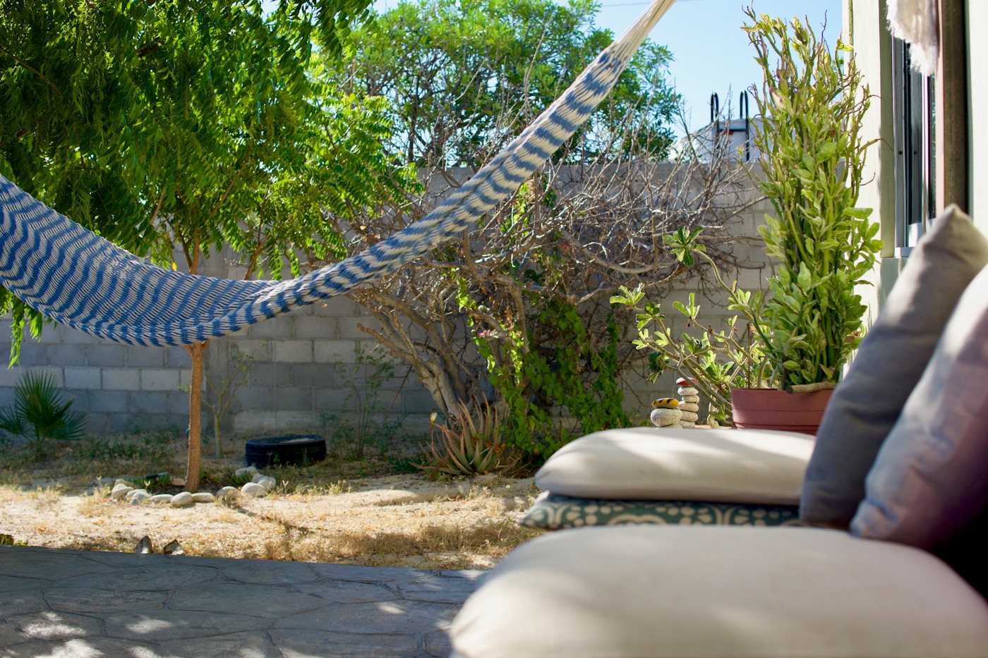 A blue and white woven hammock in a sunny backyard